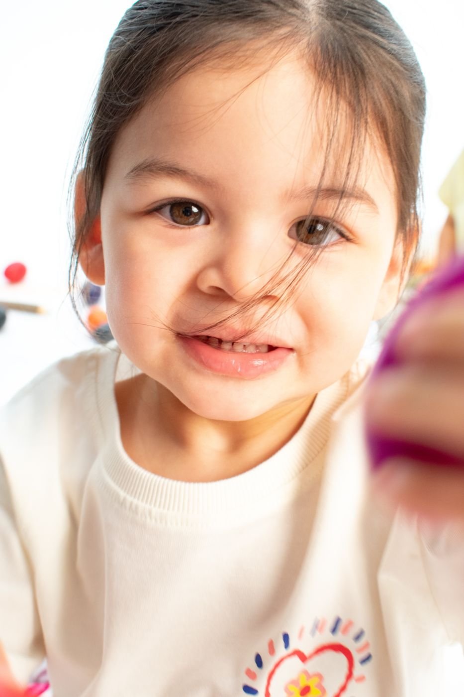 Toddler smiling closely at the camera during a painting activity